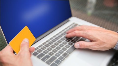 Homem ao computador a fazer pagamentos com página de Facebook aberta